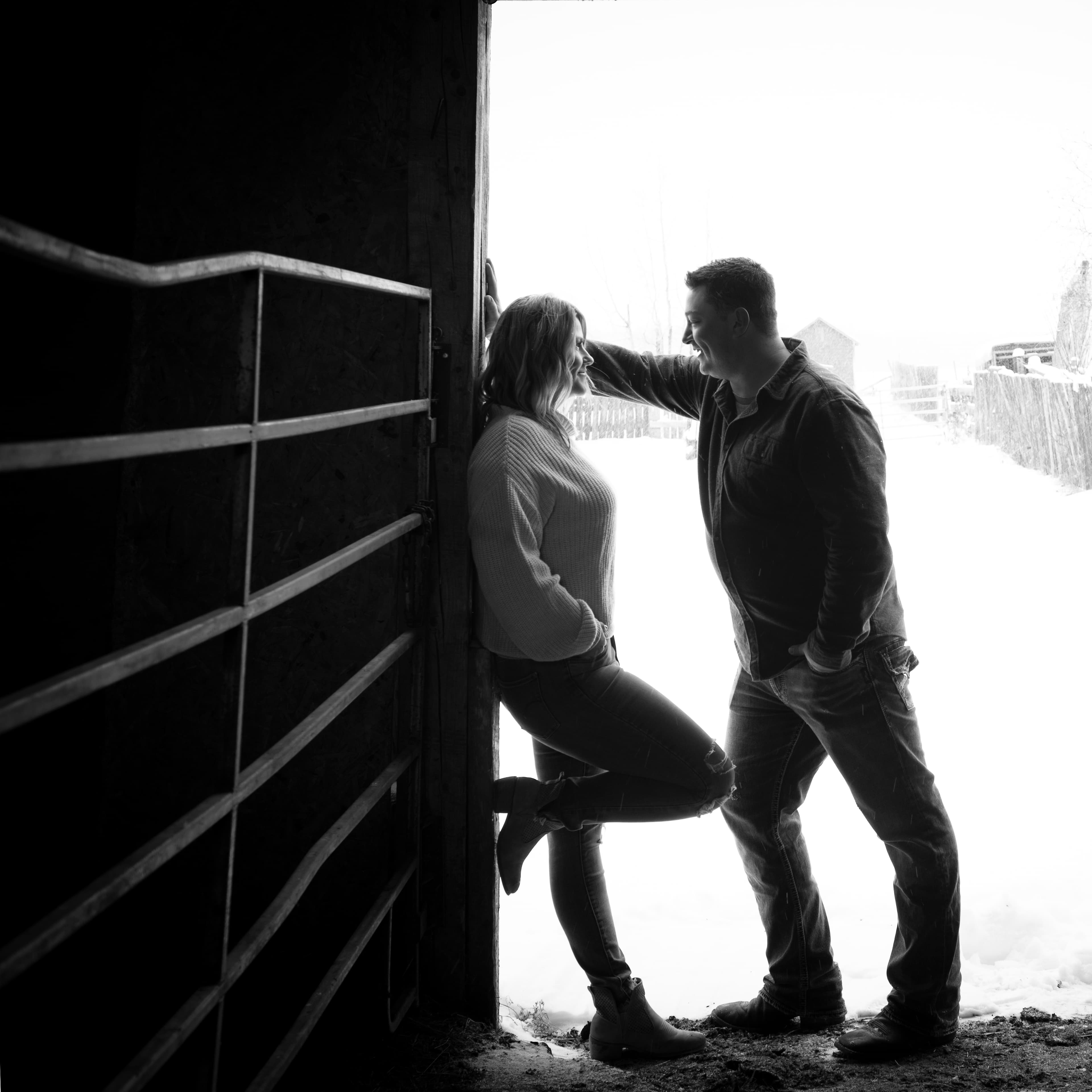 Engaged couple together in a snowy barn doorway