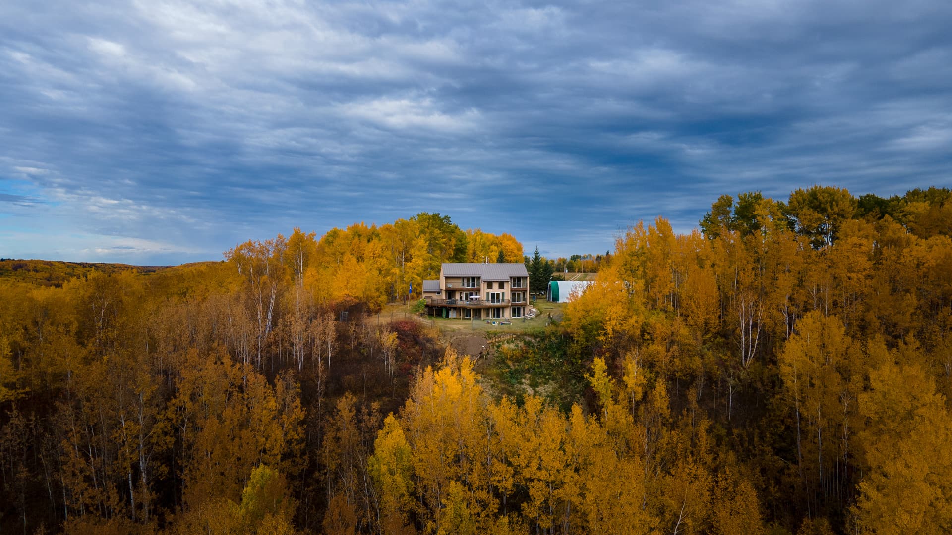 Drone view of a northern Alberta acreage surrounded by autumn forest