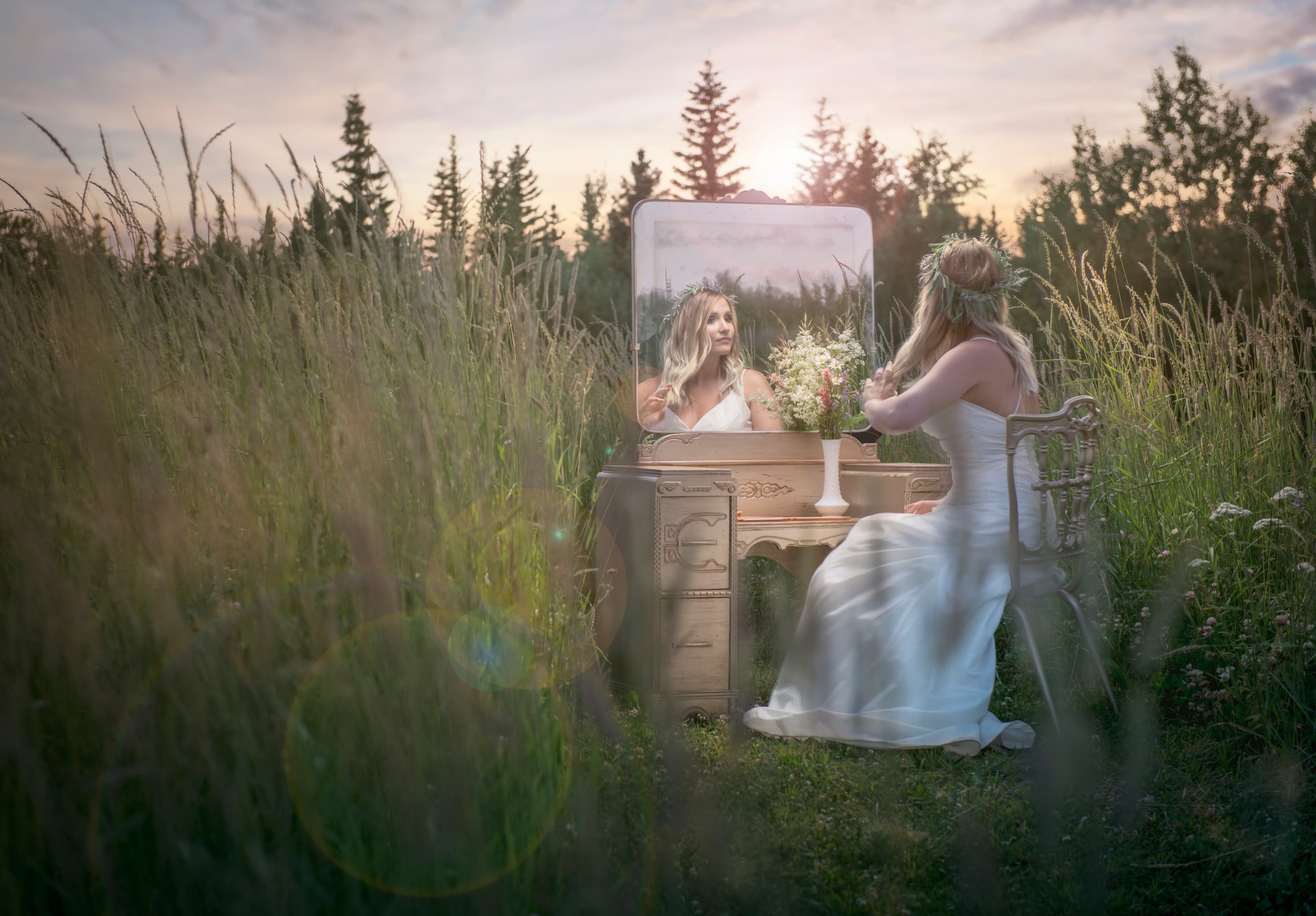 Bride seated at a vintage vanity in a meadow at sunset